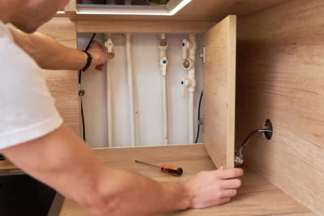 Man opens an assembly hatch and checks water pipes